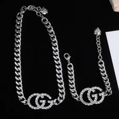 Silver chain necklace and rings arranged on black fabric