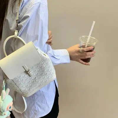 Person carrying a small white top-handle bag