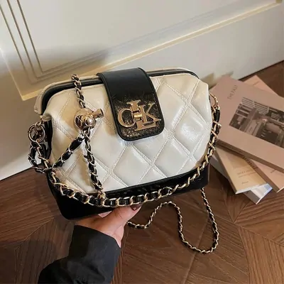 White quilted crossbody bag held in hand